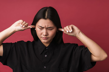 Obraz premium Displeased asian young woman covering ears