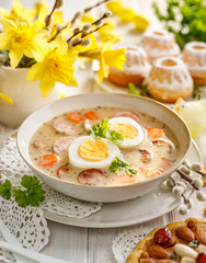 The sour soup (Żurek) polish Easter soup with the addition of sausage, hard boiled egg and vegetables in a ceramic bowl.  Traditional Easter food in Poland