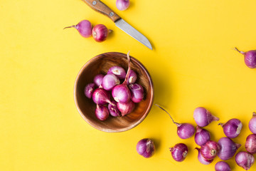 Fresh shallots-red onions on the yellow background