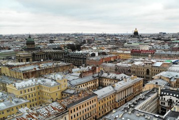Fototapeta na wymiar Aerial view of Griboyedov Canal and Kazan Cathedral and Saint Isaac's Cathedral with high traffic at winter. different roofs of citycenter of Saint-Petersburg cityscape. Sea port cranes on backstage