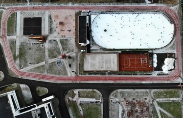 Aerial view from the top down ice rink at winter day with a lot many people skate. Treadmill around. frozen tennis court  and grass. ice-skating rink 