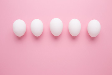 Chicken eggs in white color close-up on a pink background. A row of eggs.