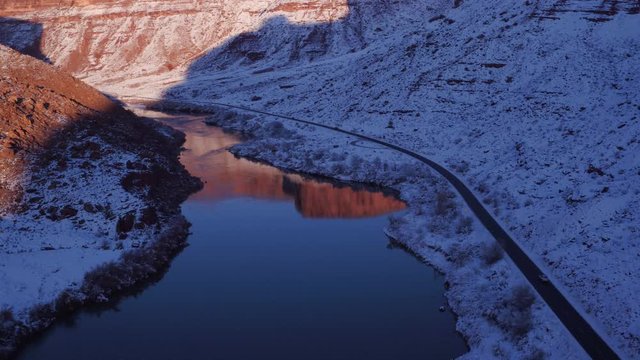 Aerial Footage Flyover of Colorado River With Reflection in Winter Near Moab, Utah U.S.A. Following Cars Approaching Below by Drone
