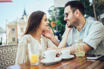 Beautiful loving couple sitting in a cafe enjoying in coffee and conversatio