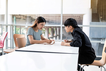 Two young teenagers doing homework together,at meeting room,blurry light around