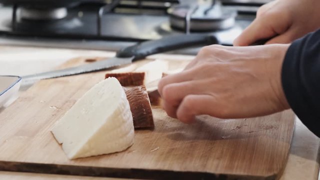 Close up footage at kitchen, woman cutting, preparing Circassian cheese on the cutting board.