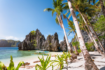 Hidden beach with first tourist trip boats in morning sun light at El Nido, Palawan, Philippines