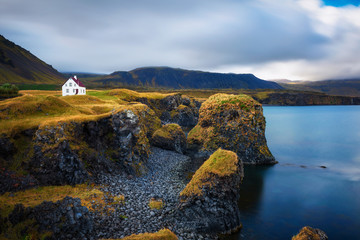 Sea shore in Iceland with cliffs and a small house in the village of Arnarstapi