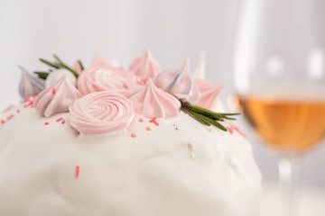 Close up view of delicious Easter cake decorated with meringue near wine glass