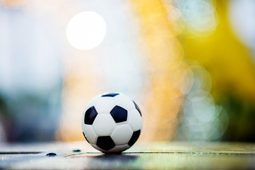 Fototapeta na wymiar The soccer ball is placed on a wooden floor and has a blurred background with beautiful bokeh.