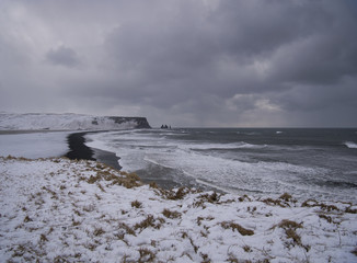 Die verschneite Küste in Island mit schwarzen Sand