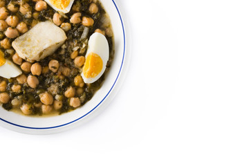 Chickpea stew with spinach and cod or potaje de vigilia isolated on white background. Top view copy space