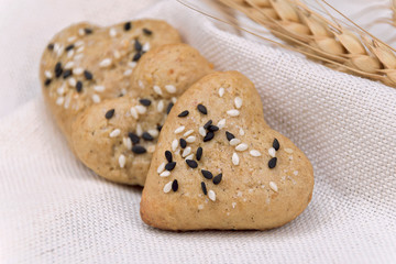 Gingerbread cookie hearts with black and white sesame and sugar on a cloth. The scene of making...