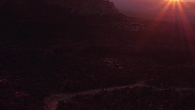 Aerial Drone Footage Following Car Down Desolate La Sals Mountains Dirt Road Near Moab, Utah U.S.A. at Sunset Dusk with Magenta Flares