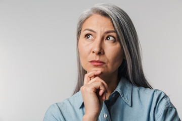 Image of adult mature woman touching chin and looking aside at empty space