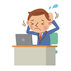 デスクでノートパソコンを使うビジネスマン（悩み・ストレスイメージ）