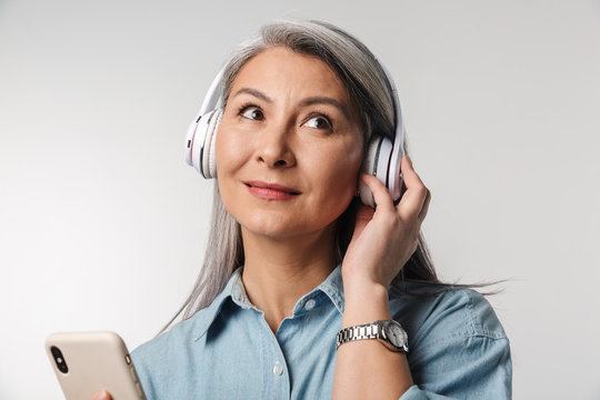 Image of adult woman with long white hair using cellphone and headphones