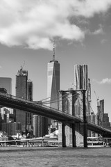 Fototapeta premium Black and White Photo of the Brooklyn Bridge with an American Flag over the East River with the Lower Manhattan New York City Skyline