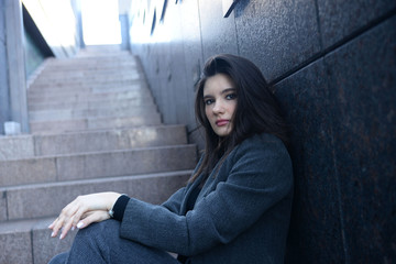 Beautiful young business woman sitting on the  stairs