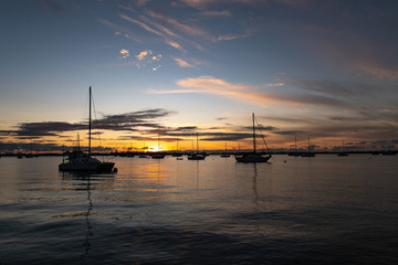 sailboats anchored together silhouette with sunset in background