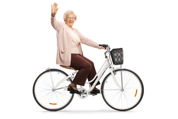 Senior woman riding a bicycle and waving at camera