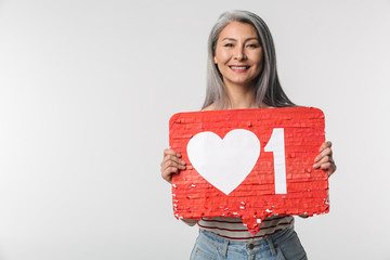 Image of adult mature happy woman holding heart like symbol on placard