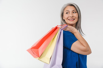 Fototapeta na wymiar Image of adult woman with long gray hair carrying paper shopping bags