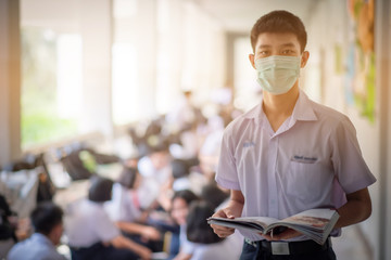 The Asian high school students in the white school uniforms wearing the mask to reading the books to prepare final exams in the midst of Coronavirus disease 2019 (COVID-19) epidemic. - Powered by Adobe