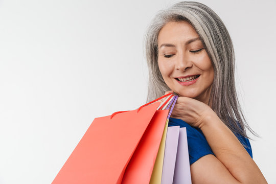 Image of adult woman with long gray hair carrying paper shopping bags