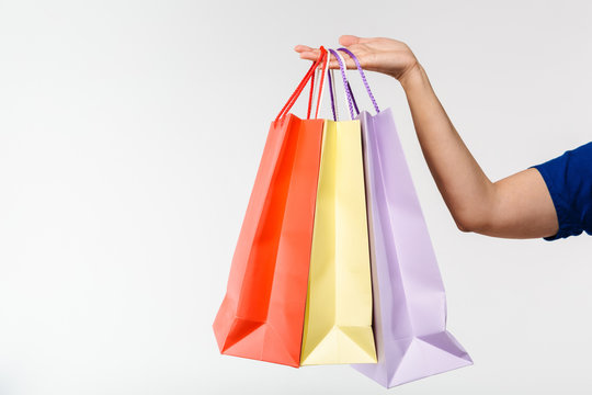 Cropped image of female shopper carrying colorful paper shopping bags