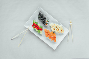 Large sushi plate with chopsticks on bright background, asian food on plate