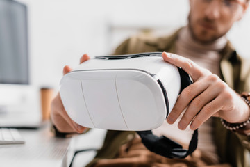 Selective focus of 3d artist holding virtual reality headset at table