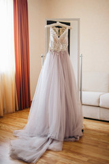 Fototapeta na wymiar Purple wedding dress hanging on a mirror in the room