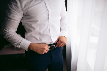 Obraz premium Man tightens the black leather belt on the black pants