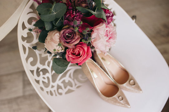 Luxury wedding shoes and flowers with roses on the ahite chair