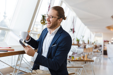 Positive handsome young businessman holding clipboard