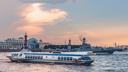 tourist fast ship against the background of a warship on the Neva in St. Petersburg and blue sky and the city