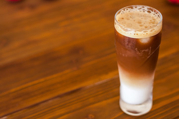 A glass of the cold frappe on a wooden table.
