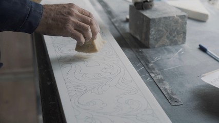Engraver puts a varnish on a stone plate, that will fix the drawn ornament