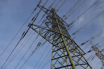 Grüner Starkstrommast ragt in den blauen Himmel