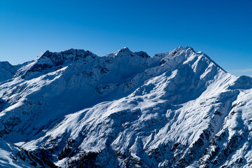Fototapeta na wymiar European winter sports Alps - snowy peaks, mountains and ski slopes with blue skies near St. Anton am Arlberg
