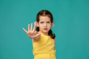 Cute little child girl making stop gesture on blue background. focus on hand