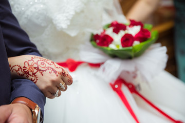 Let's get into the groom's arms. The bride holds a red bouquet in her hand. Hands and fingers are...