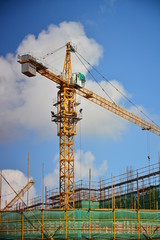 Large tower crane on construction site with blue sky and white clouds