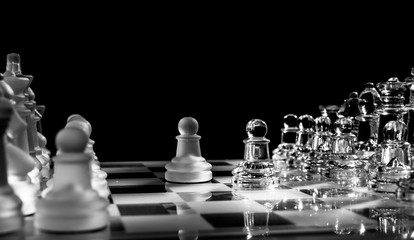 Glass or crystal chess set with opposing pawn pieses isolated on black background with copy space....