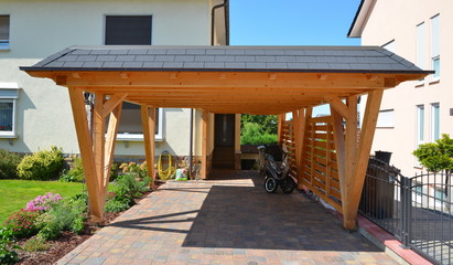 Neuer Carport aus lasiertem Holz mit beschichteten Metall-Schindeln und Dachrinne