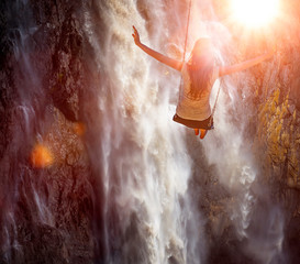 Eine Frau schaukelt vor einem Wasserfall