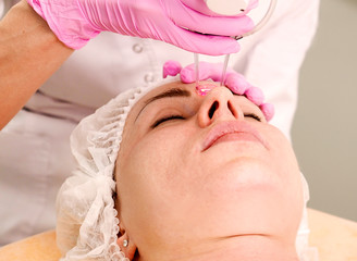 Closeup photo of woman having face polishing procedure in beauty salon.Doctor cosmetologist makes the procedure using professional laser system to a woman patient. Laser resurfacing and face treatment