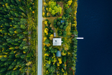 Aerial top view of log cabin  or cottage with road in spring forest by the lake in Finland