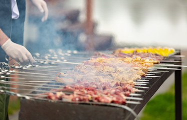 cook in gloves cooks kebab, during cooking rotates skewer with meat